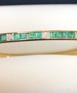 Pulsera de media caña con esmeraldas en carre y 0'14 cts de brillantes, realizada en oro amarillo de ley 18 kts.