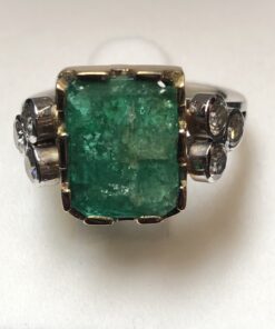 Sortija vintage con esmeralda central de 4'20 cts enriquecida con 6 brillantes laterales de 0'35 cts en total, realizada en oro blanco y amarillo de ley 18 kts.