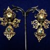 Pendientes populares del siglo XIX, de tres cuerpos: botón, lazo y perilla colgante, cuajados de esmeraldas (2 cts aprox.) y adornos de filigrana. Realizados en oro de ley 18 kts. 5.5 cm de alto