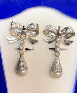 Pendientes largos vintage (años 60) en forma de lazada con remate de perlas cultivadas y cuajados de brillantes, realizados en oro de ley 18 kts.