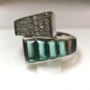 Sortija con brazos contrapeados cuajados de 0'38 cts de brillantes en total y 0'70 cts de esmeraldas talla baguette, montados en oro blanco de ley 18 kts.
