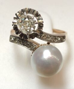Sortija "tú y yo" vintage (años 60) con perla natural de bonito oriente y brillante de 0'40 cts, enriquecida con brillantitos en los brazos. Realizada en oro de ley 18 kts.