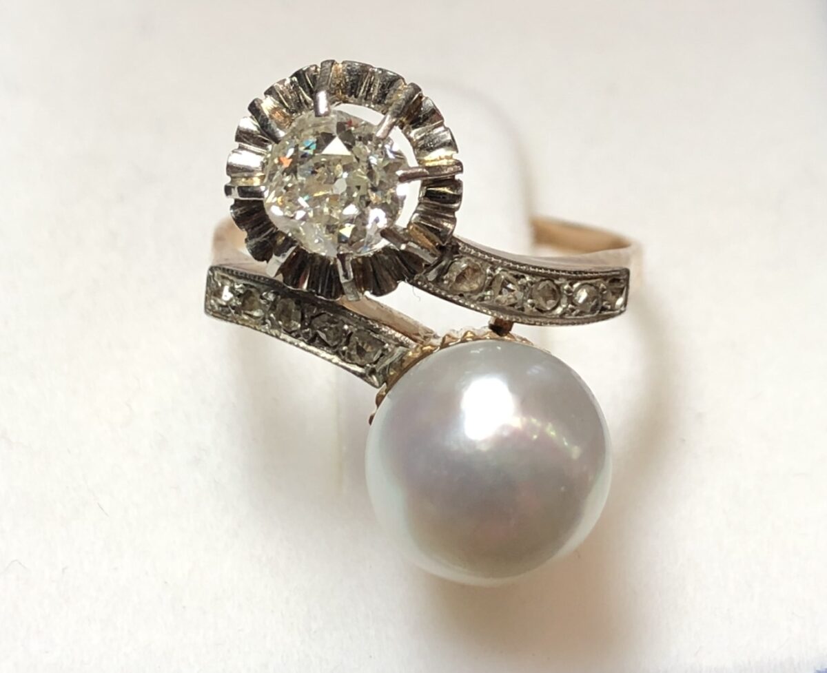 Sortija "tú y yo" vintage (años 60) con perla natural de bonito oriente y brillante de 0'40 cts, enriquecida con brillantitos en los brazos. Realizada en oro de ley 18 kts.