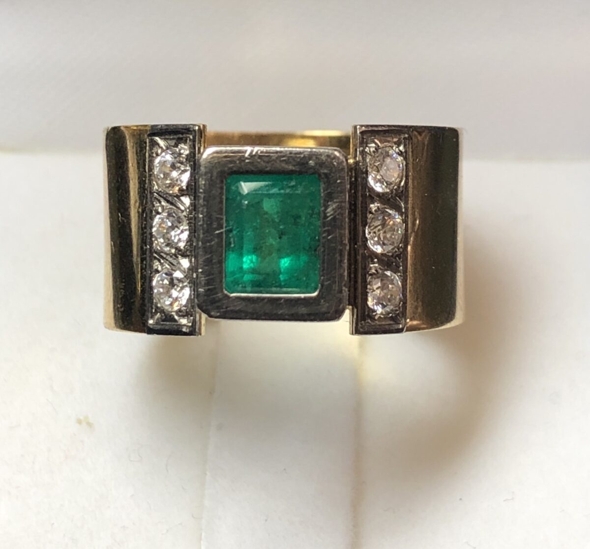 Sortija ancha con auténtica esmeralda colombiana de 0'80 cts y brillantes laterales de 0'30 cts en total, realizada en oro blanco y amarillo de ley 18 kts.