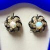 Bonitos pendientes de finales del s. XIX en forma de rosetones con ópalos blancos y 0'50 cts de diamantes, realizados en oro amarillo de ley 18 kts con esmaltado negro.