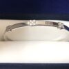 Pulsera rígida con 3 motivos florales y 0'15 cts de brillantes, realizada en oro blanco de ley 18 kts.