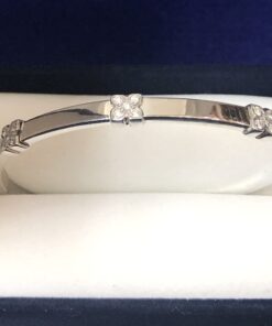 Pulsera rígida con 3 motivos florales y 0'15 cts de brillantes, realizada en oro blanco de ley 18 kts.