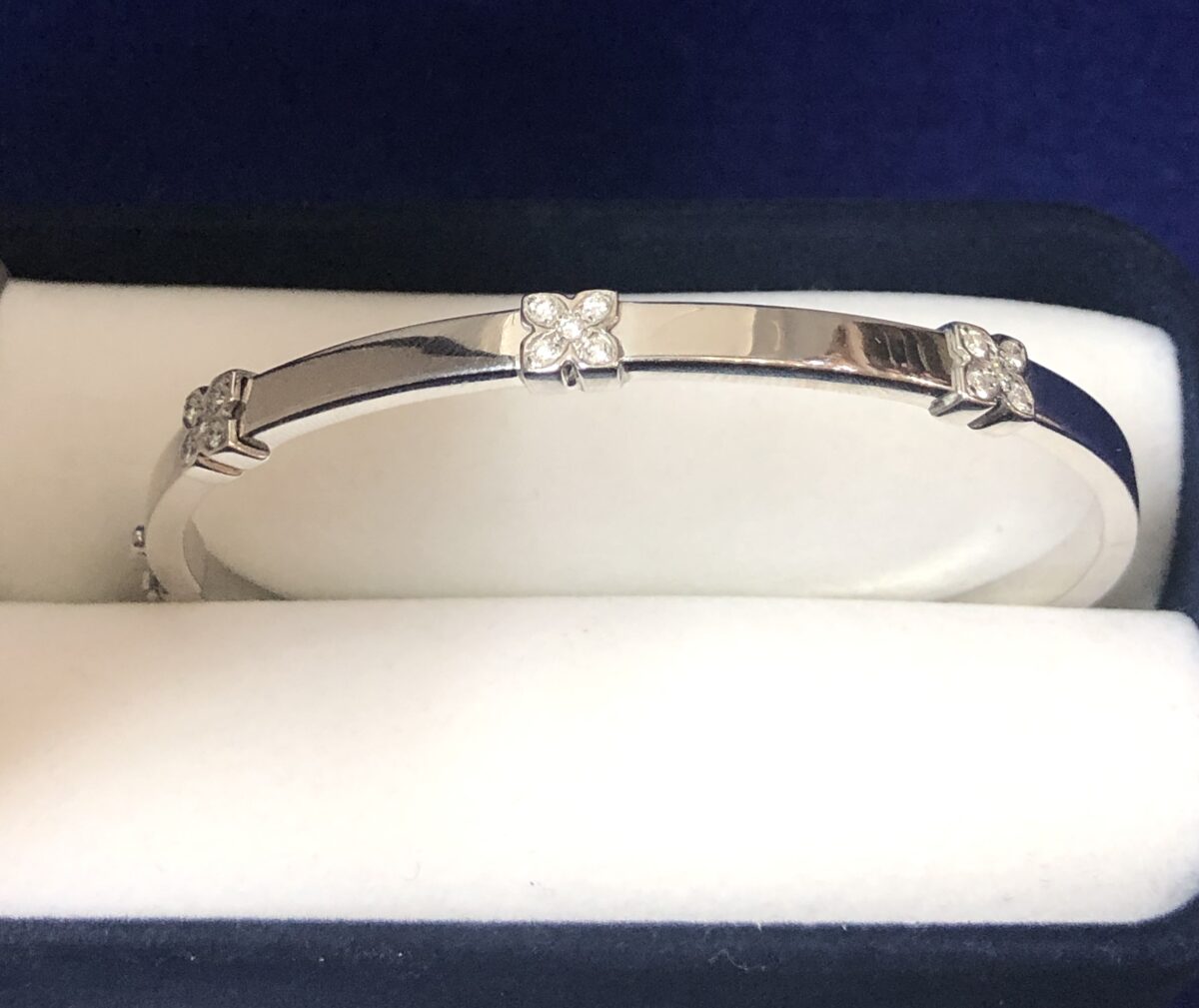 Pulsera rígida con 3 motivos florales y 0'15 cts de brillantes, realizada en oro blanco de ley 18 kts.