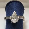 Sortija de pedida con diamante central talla pera de 1'40 cts, color J-SI y diamantes laterales en baguette de 0'10 cts cada uno, color H-VS1.