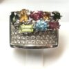 Sortija ancha con distintas gemas de colores y pavé de brillantes de 0'40 cts en total, realizada en oro blanco de ley 18 kts.