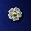 Broche en forma de flor cuajado de brillantes en pavé, zafiros y topacios, realizado en oro blanco de ley 18 kts.