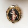 Precioso broche del s. XIX con imagen de Cupido pintada a mano sobre nácar y decorado con diamantes talla antigua, realizado en oro amarillo de ley 18 kts.