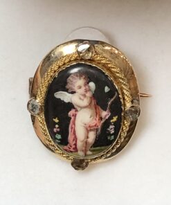 Precioso broche del s. XIX con imagen de Cupido pintada a mano sobre nácar y decorado con diamantes talla antigua, realizado en oro amarillo de ley 18 kts.
