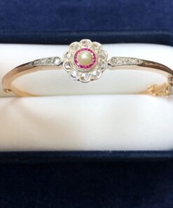 Bonita pulsera de pedida Art Decó con rosetón de 0'50 cts de diamantes, rubíes calibrados y centro de perla, realizada eb oro de ley 18 kts.