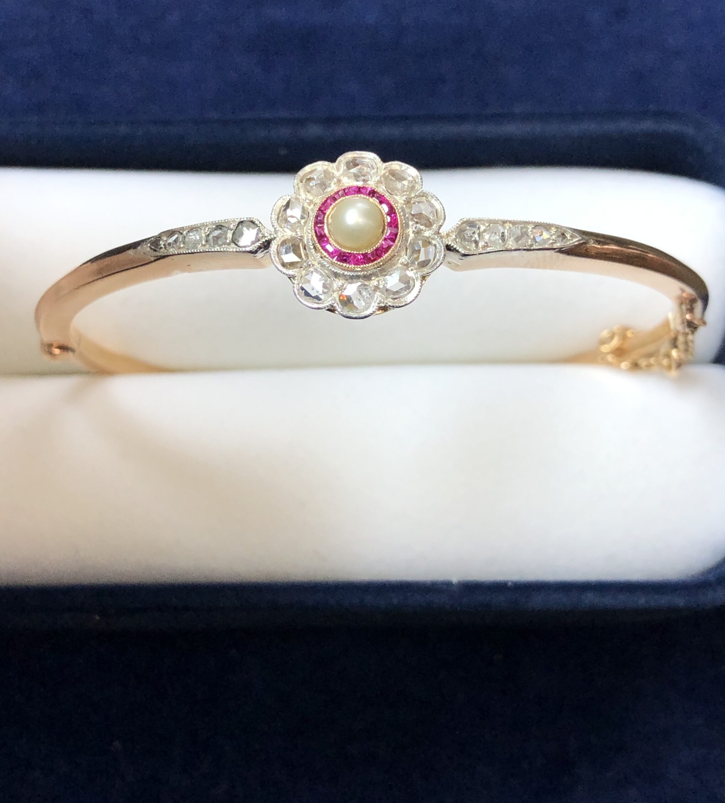 Bonita pulsera de pedida Art Decó con rosetón de 0'50 cts de diamantes, rubíes calibrados y centro de perla, realizada eb oro de ley 18 kts.