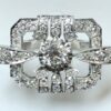 Sortija en forma de hebilla cuajada de brillantes (2,30 cts en total) con diamante central de 0'50 cts, realizada en oro blanco de ley 18 kts.